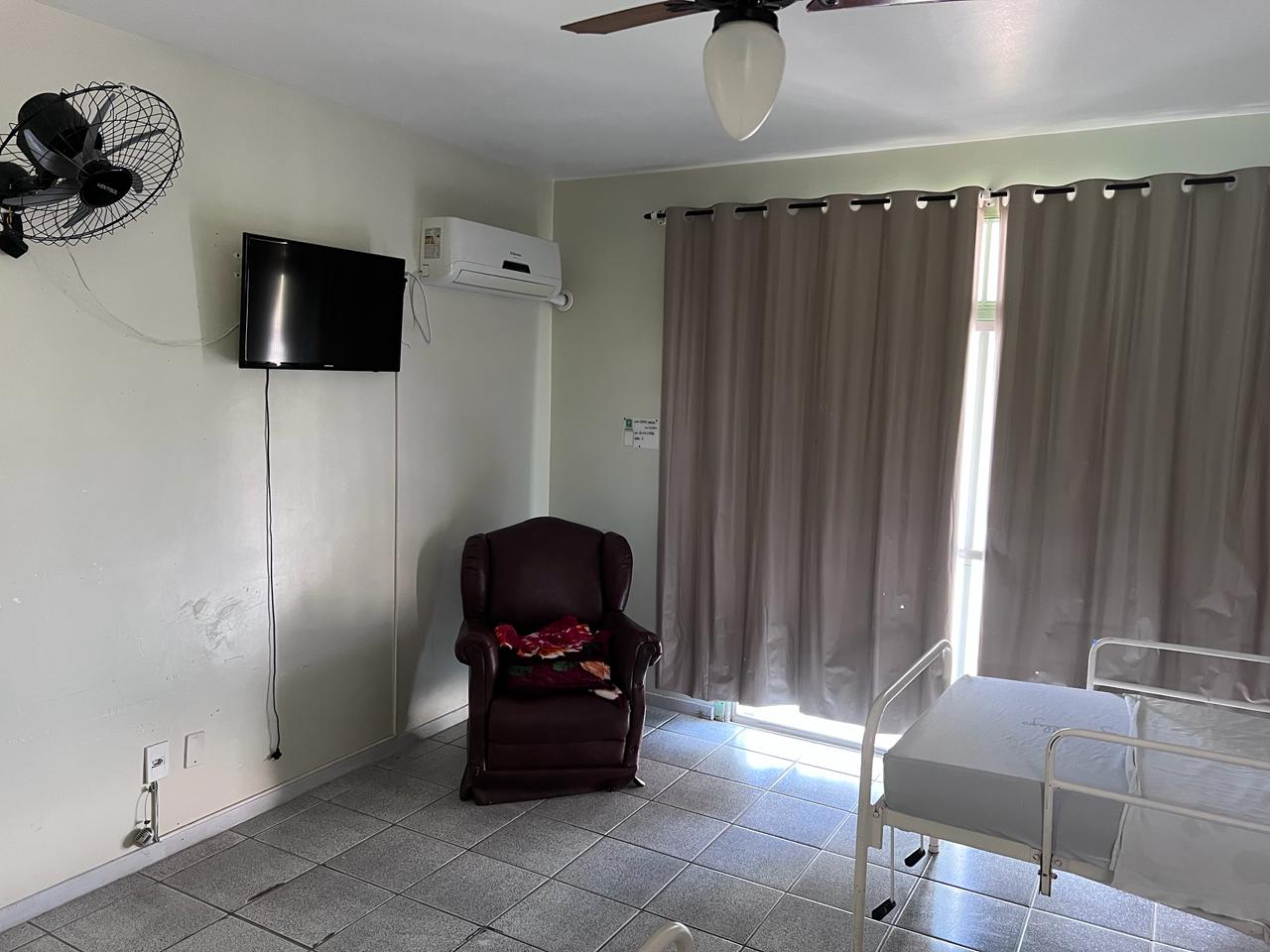 Quarto com TV, poltrona e ventilação